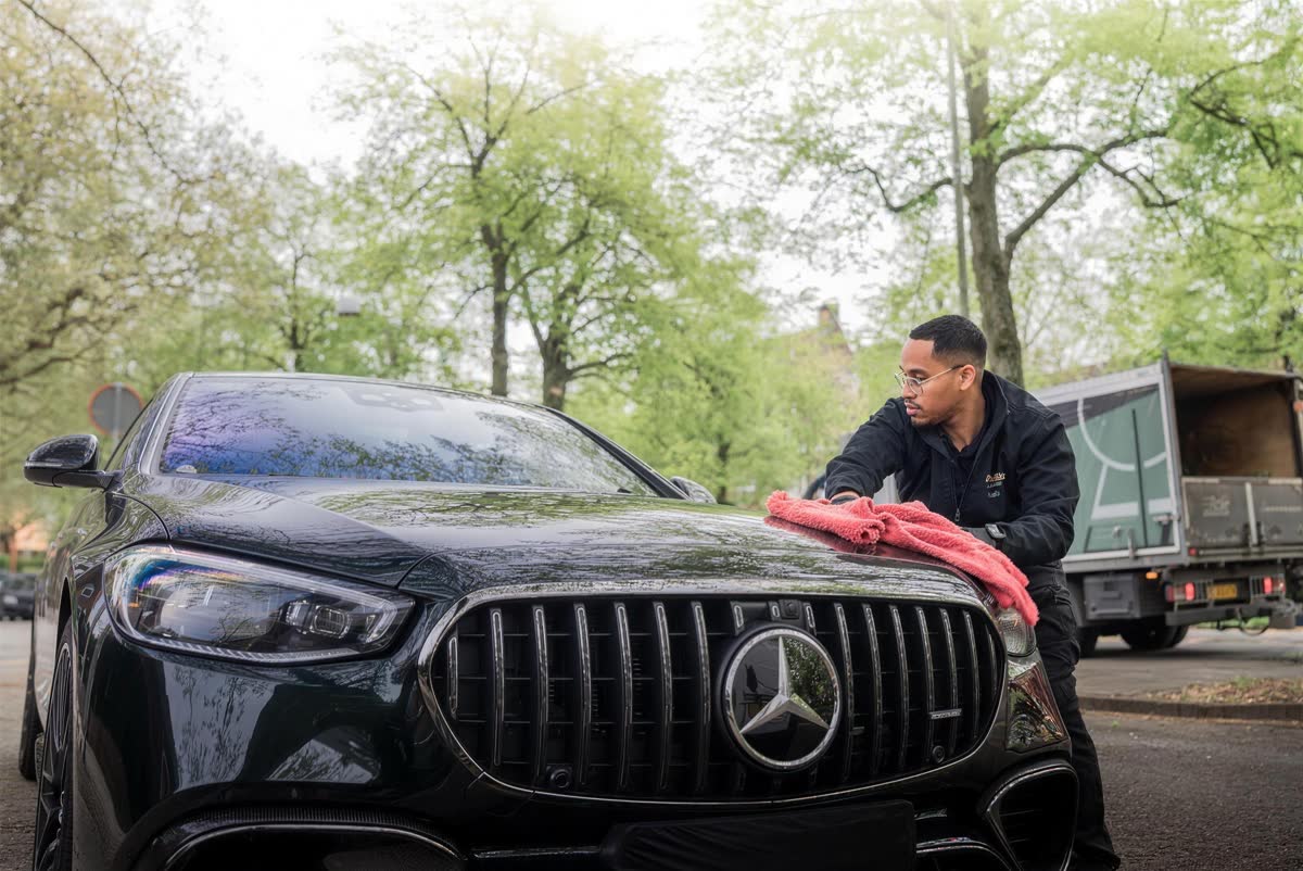 A SPOTWASH detailer hand-drying a black Mercedes on location.